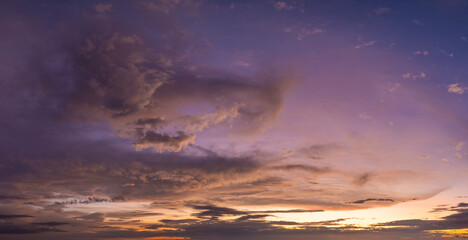 Colorful sunset sky with setting sun behind vivid orange and yellow clouds