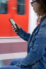 Pretty young girl looking at her phone in the train station