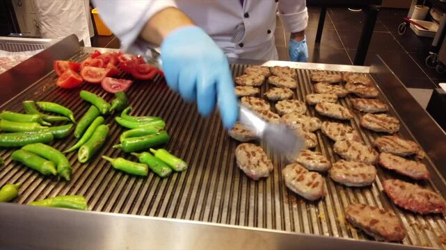 Chef grilling kofta on a hot grill, skillfully turning them with tongs in a bustling restaurant kitchen