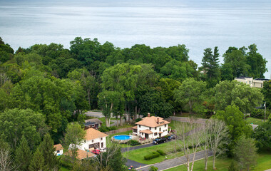 Private residential house in lakeside suburban sprawl area in Rochester, New York. Upscale suburban home with large backyard swimming pool and green grassy lawn in summer season