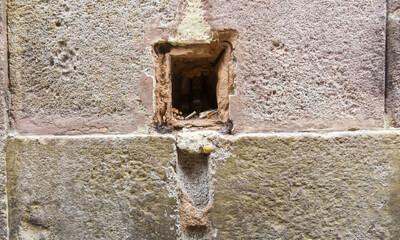 a hole in a stone wall with lots of cigarettebutts in the inside
