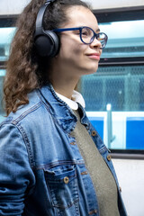 Pretty young girl listening to music with headphones inside the train