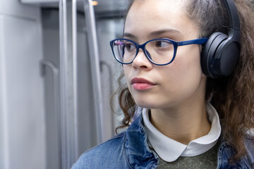 Pretty young girl listening to music with headphones inside the train
