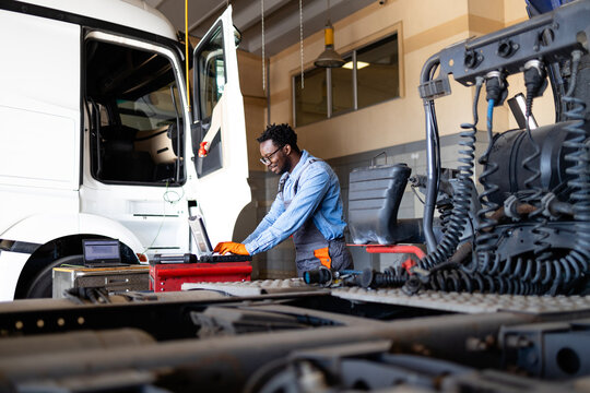 Professional truck repairman servicing the vehicle inside workshop.