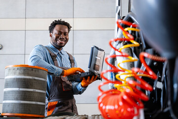 Portrait of experienced truck serviceman using laptop computer and repairing the vehicle.