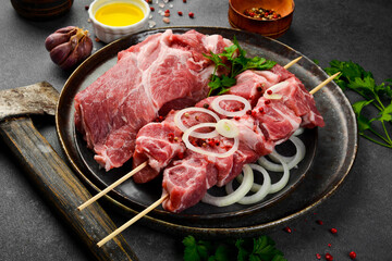 Raw pork kebab on wooden skewers. Preparation of meat dishes. On a gray stone background.