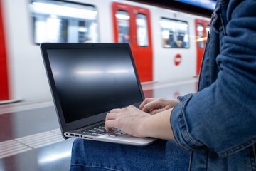 Girl waiting for the train and using her laptop