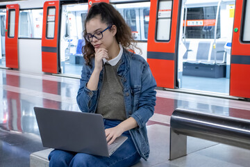 Girl waiting for the train and using her laptop
