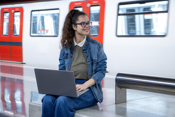 Girl waiting for the train and using her laptop