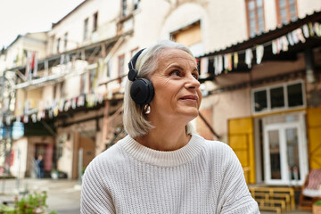 A joyful woman listens to music with headphones, appreciating the vibrant surroundings.