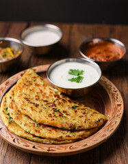 Delicious aloo paratha served with sauces on wooden table. Tasty food. Delicious snack. Close-up.