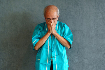 Elderly man with pain and illness standing on black wall background