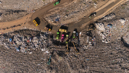 The truck is collecting garbage in a large garbage pile.