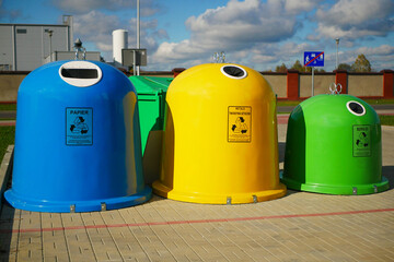 A garbage sorting station with large, brightly colored bins in yellow, green, and blue.