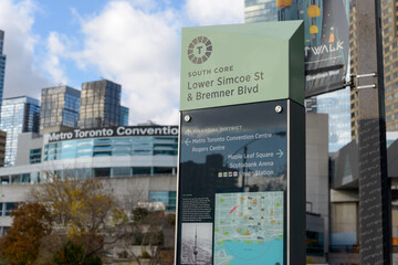 Naklejka premium City of Toronto location marker at South Core (Lower Simcoe St & Bremner St) with directions and map and a defocused view of the convention centre downtown