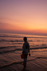Fototapeta premium a boy is standing in the water with a bucket and bucket
