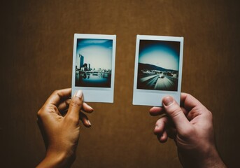 Hands holding vintage instant photos against brown background