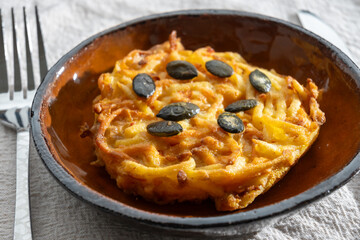 Pumpkin grated roasted patties, rosti or latkes, made fron squash and potato decorated with pumpkin seeds