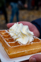 Tasty dessert, French or Luxembourg waffles with whipped cream close up eating outdoor in autumn