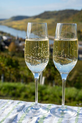 Tasting sparkling white wine, traditional champagne method making of cremant in caves on Moselle river valley in Luxembourg, glasses of wine and view on terraced vineyards