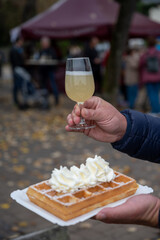 Wine festival in Schengen, Luxembourg, French or Luxembourg waffle with whipped cream and glass of young wine eating outdoor in autumn