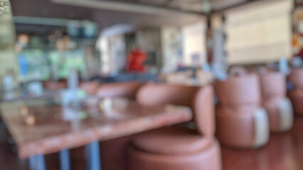 Defocused abstract background of cafe or restaurant interior design. Wooden table, wooden chairs and empty sofa in elegant and luxurious style with blur background. Cafe interior concept