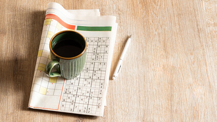 crossword paper with pen and coffee cup