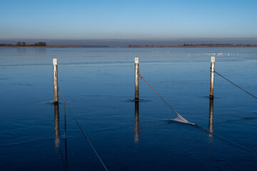 A view of empty docks in the winter. Blue water and a clear blue sky