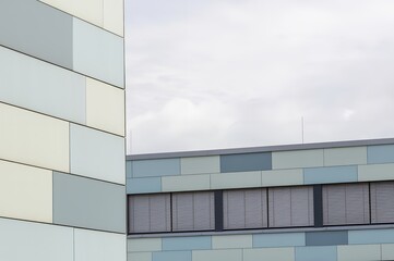 Modern building exterior showing colorful pastel paneling and windows with venetian blinds