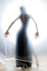Fototapeta premium Mysterious Woman Behind Frosted Plastic Sheet in Abstract Studio Setting