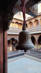 Obraz premium Decoratively engraved temple bell hangs from a wooden frame, overlooking a serene courtyard