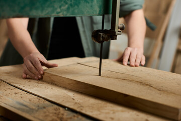 Focused on her task, a female carpenter expertly cuts wood, showcasing her craftsmanship and dedication.