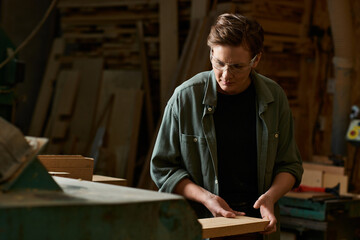 In a bustling workshop, a female carpenter meticulously crafts wood, showcasing her craftsmanship and passion.