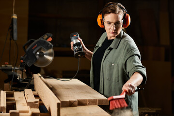 In her workshop, a talented female carpenter focuses on shaping wood while expertly managing her...