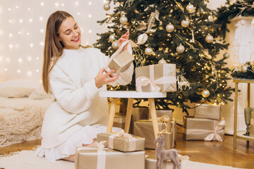 Woman arranging christmas gifts under decorated tree