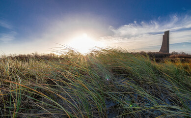 Strandhafer am Ostseestrand im Wechselspiel mit Wind und Sonne. Im Hintergrund das Marine Denkmal...