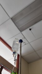 low angle of an iron stand to hang saline bottle high to deliver saline on patient. Doctor gives saline solution to patient through vein. Medical concept