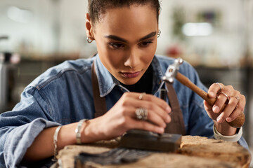 A skilled artisan meticulously designs fine jewelry while surrounded by tools and gems.
