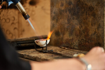 A skilled craftsman uses a torch to create stunning jewelry in an artisan workshop.