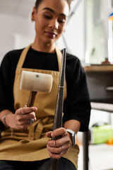 A skilled woman shapes metal with precision while surrounded by artistic materials and tools.