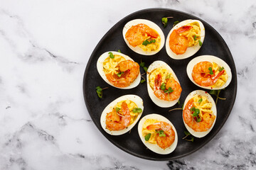 Boiled eggs stuffed with yolk and seasoned with mayonnaise, stuffed eggs with shrimp, on a black plate, selective focus, close-up, no people,