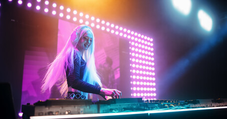 Talented Female Artist Performing a DJ Set on Turntables Live on Stage. Young Beautiful Woman...
