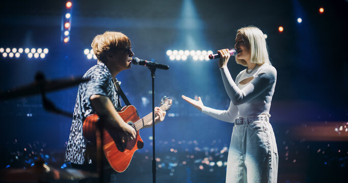 Pop Duo Collaboration With a Male Singer Playing Acoustic Guitar and Female Star Singing on Stage. Folk Guitarist Strums Passionately While RnB Female Performer Sings with Heartfelt Emotion