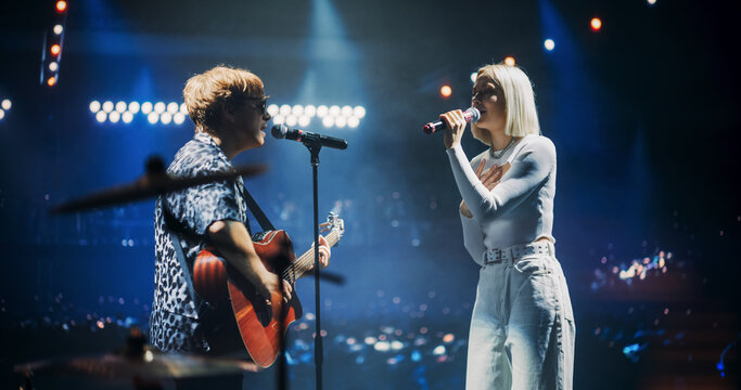Pop Duo Collaboration With a Male Singer Playing Acoustic Guitar and Female Star Singing on Stage. Folk Guitarist Strums Passionately While RnB Female Performer Sings with Heartfelt Emotion