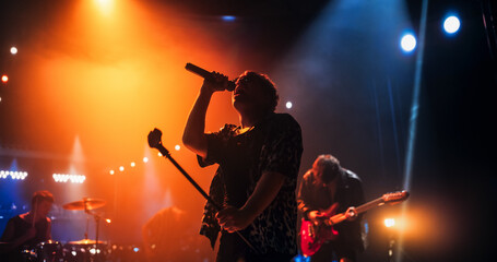 Portrait of a Lead Singer Performing at a Rock Concert Live on Stage with Confetti. Talented Musician Bringing His Unique Attitude, Playing Energetic Rock Hits. Young Band Playing For the Crowd