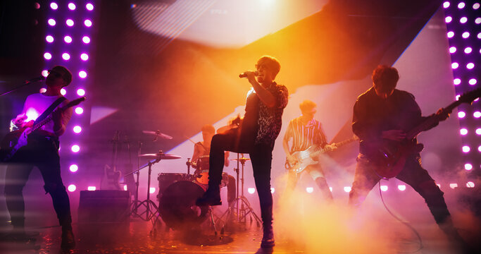 Energetic Rock Band Performing on a Nightclub Stage with Dynamic Lights, Animated LED Screen and Special Effects. Rock Music Artists Creating a Unique Show Experience With Powerful Alternative Music