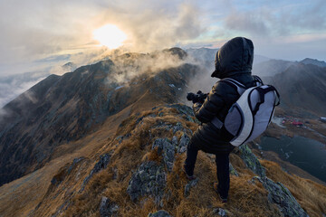 Woman with camera hiking on a trail in the mountains