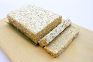 Some slices of raw tempeh on a white background. Tempeh is a nutrient- and protein-rich food with affordable retail prices in traditional markets.