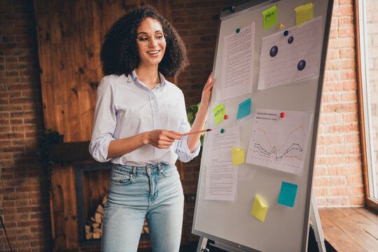 Smiling businesswoman presenting data analysis on chart in modern office with natural daylight