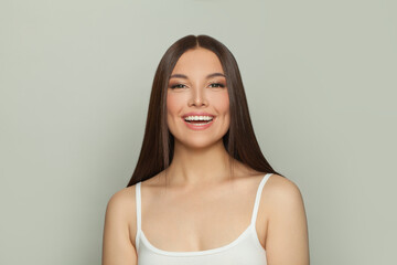 Laughing brunette woman with glowing skin, subtle makeup and a gentle smile. Young model posing, portrait